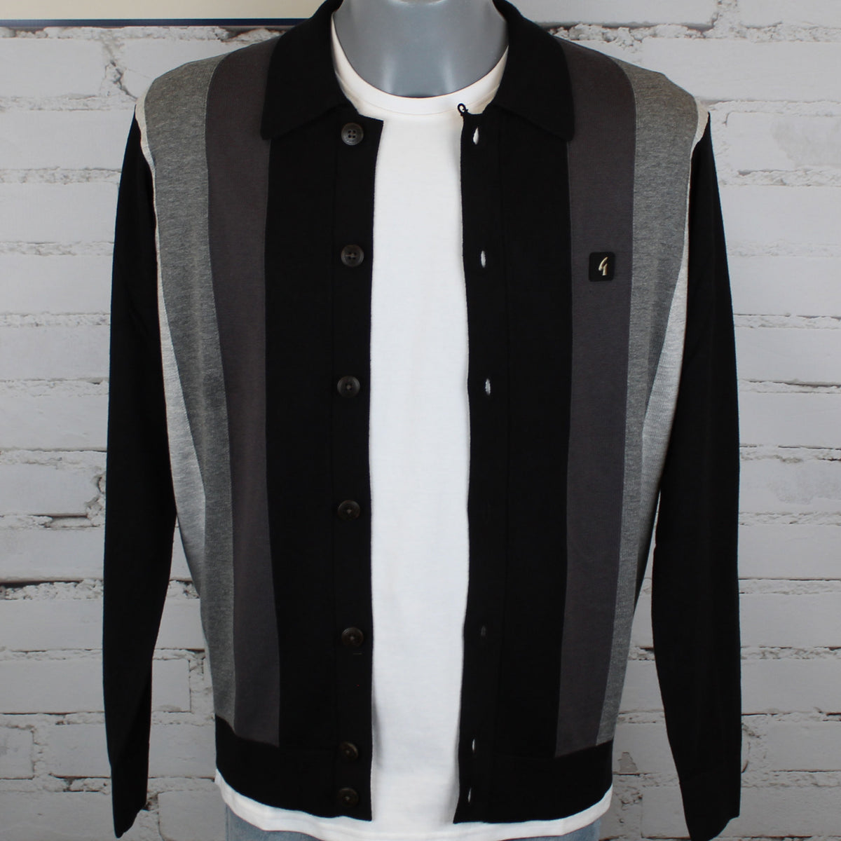 A men's colorblock knit cardigan sweater displayed on a gray mannequin torso. The cardigan features vertical stripes of black, dark gray, and heather gray, worn over a white t-shirt.